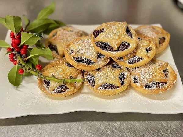 Freshly baked homemade mince pies, golden and flaky, dusted with icing sugar, served on white trays at The Garden Kitchen in Bewdley.