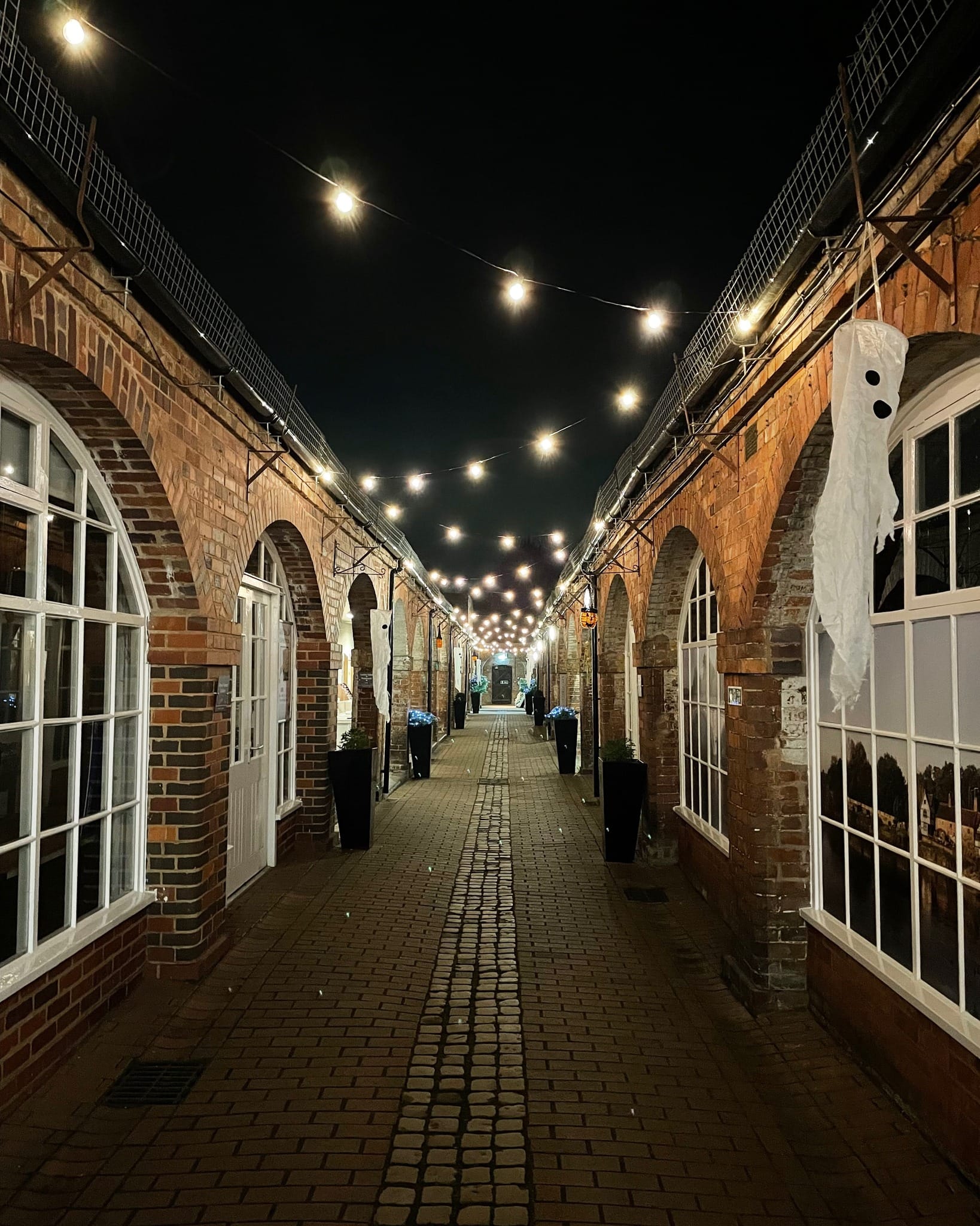Halloween Decorations in Bewdley Museum Courtyard A view of the lit-up courtyard at Bewdley Museum at night, decorated with string lights and hanging ghost decorations for Halloween.