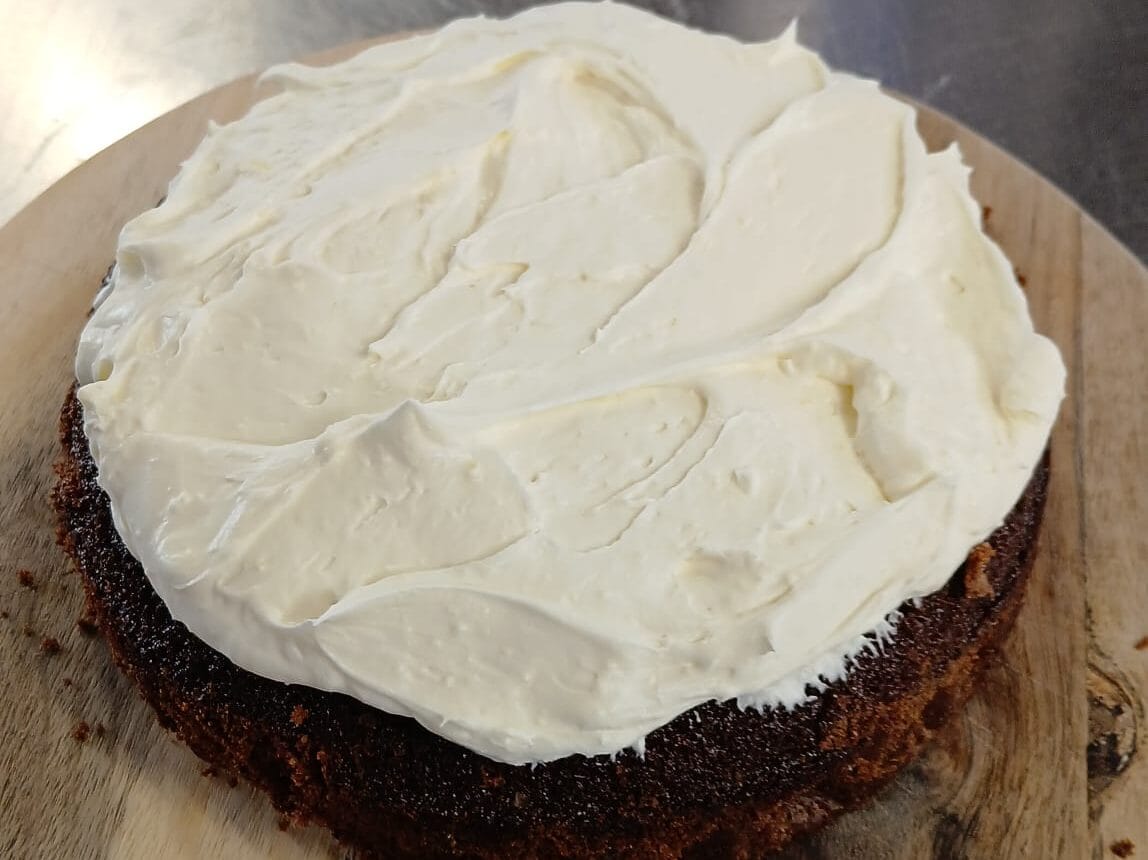 Chocolate Guinness Cake with Cream Cheese Frosting A rich, dark chocolate Guinness cake topped with a thick layer of smooth cream cheese frosting. Baked for St. Patrick’s Day, this moist and indulgent cake sits on a rustic wooden board, ready to be sliced and served.